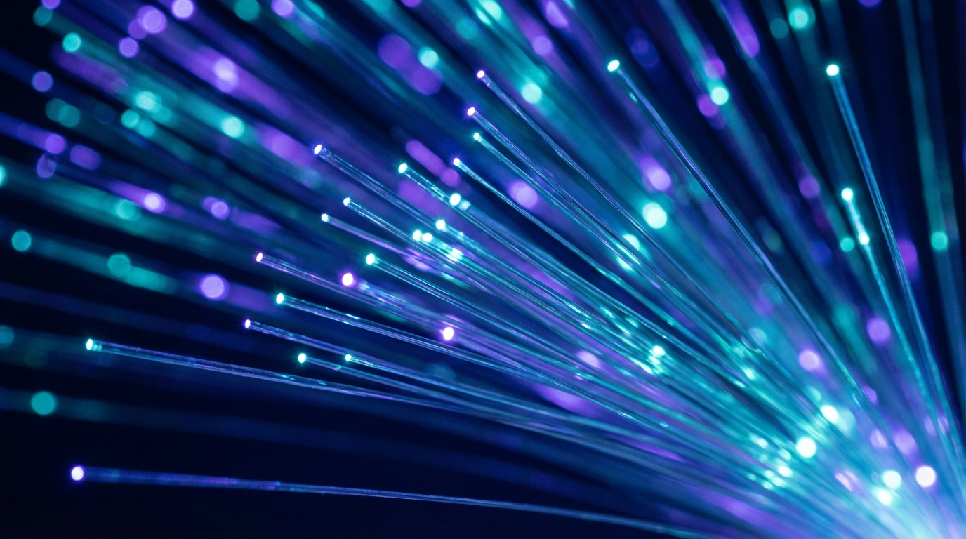 A close up of fiber optic cables with glowing light trails in blue and purple tones to convey speed and reliable data flow.